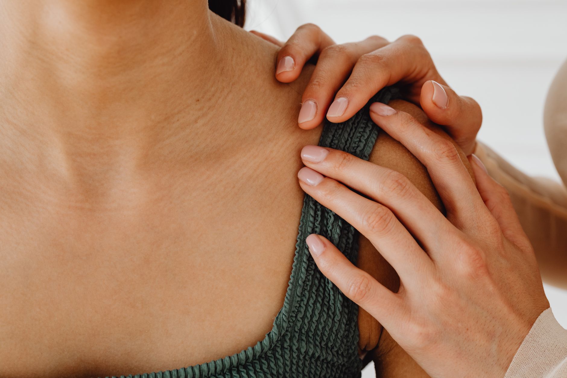 A steadying hand resting on a grieving person's shoulder